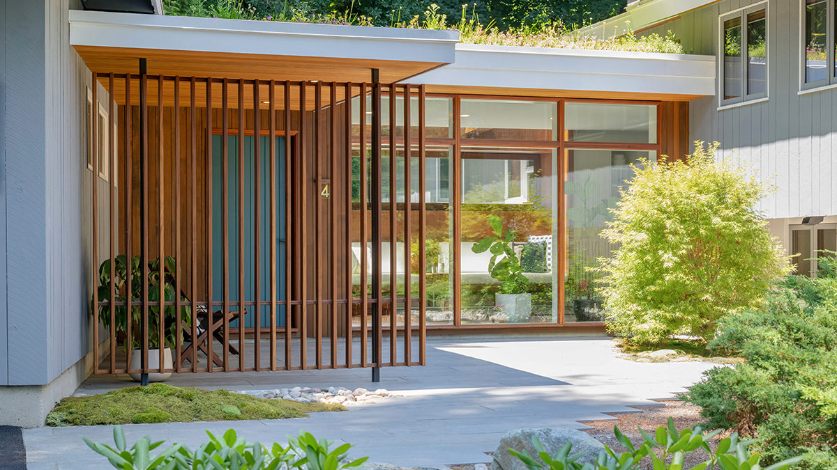 Mid-century modern breezeway with a large mahogany slat wall, floor to ceiling windows, extensive landscaping and a live sedum roof