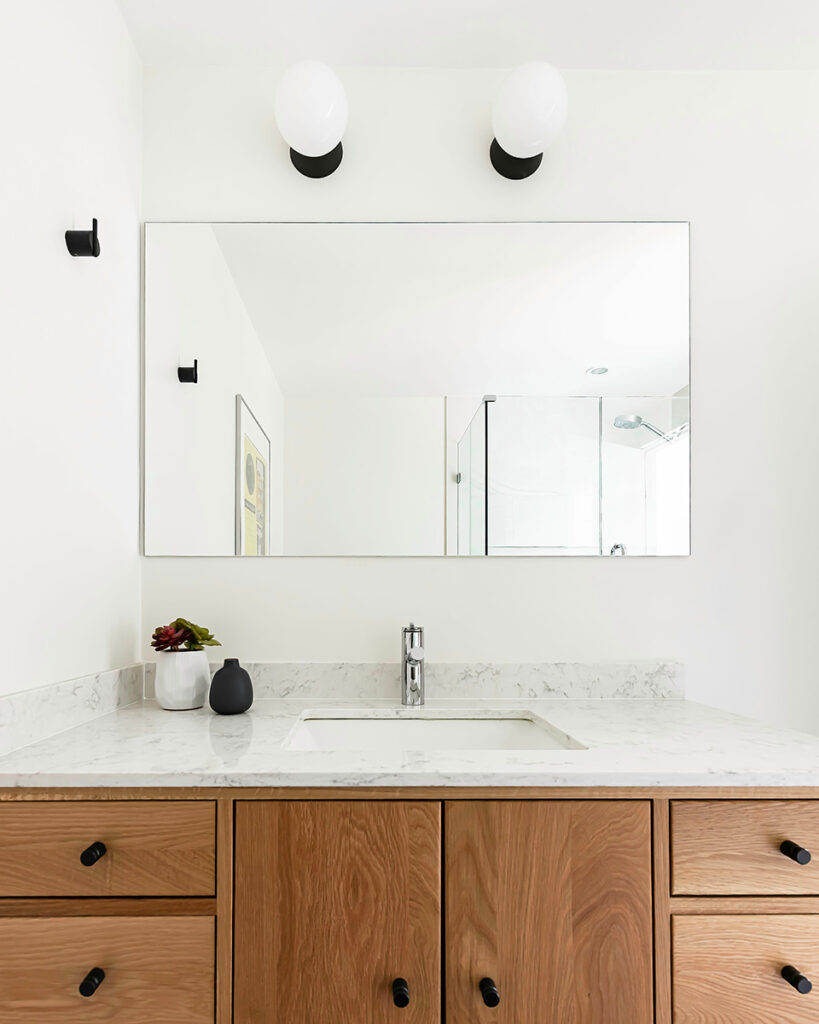 Scandinavian minimalist bathroom with large glass mirror, white oak vanity and black hardware